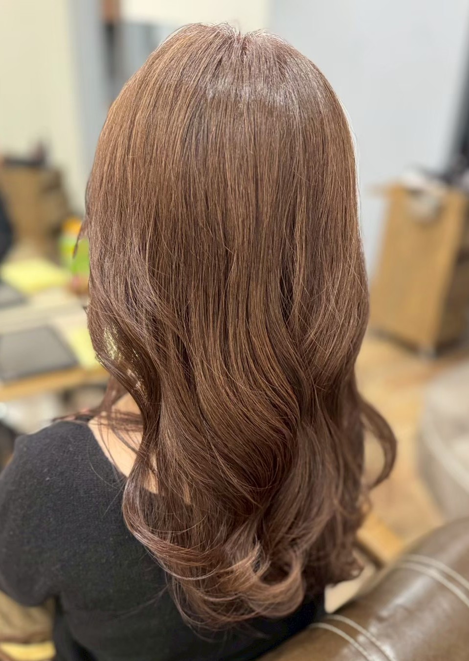 ブラウンのロングヘアに毛先を中心とした柔らかなカールがついた後ろ姿