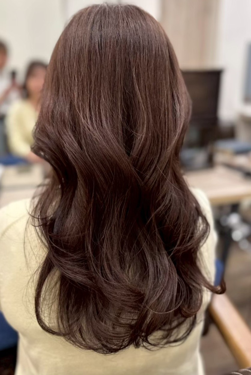 ダークブラウンのロングヘアに毛先を中心とした柔らかなカールがついた後ろ姿